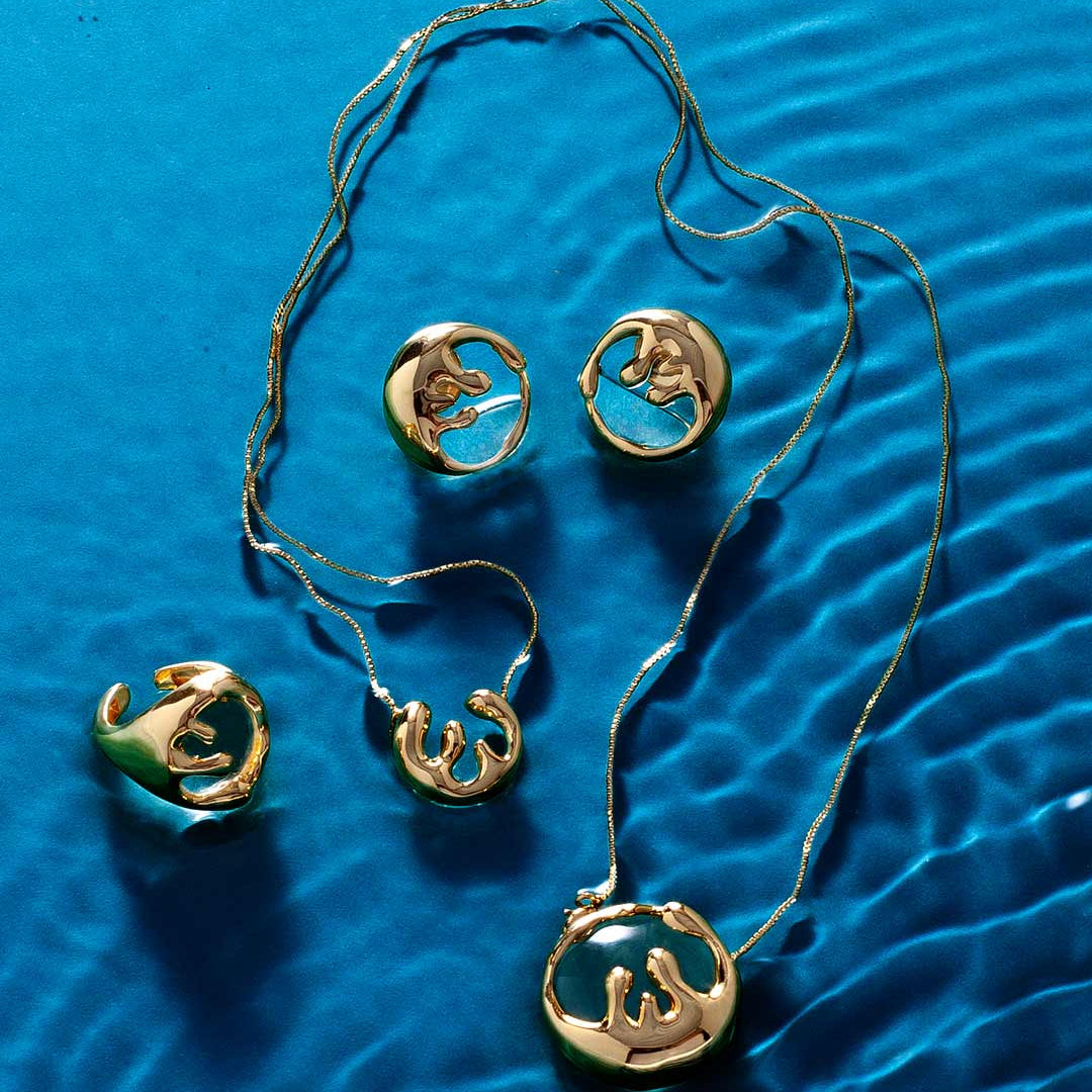 Modern organic gold jewelry collection styled on water-inspired background