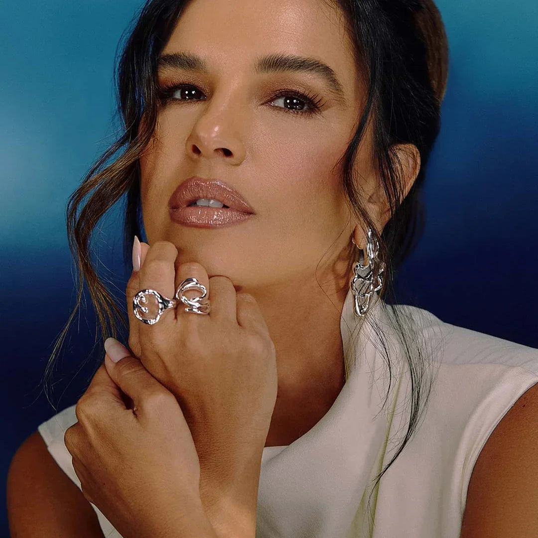 Woman wearing sculptural organic silver ring and matching statement earrings