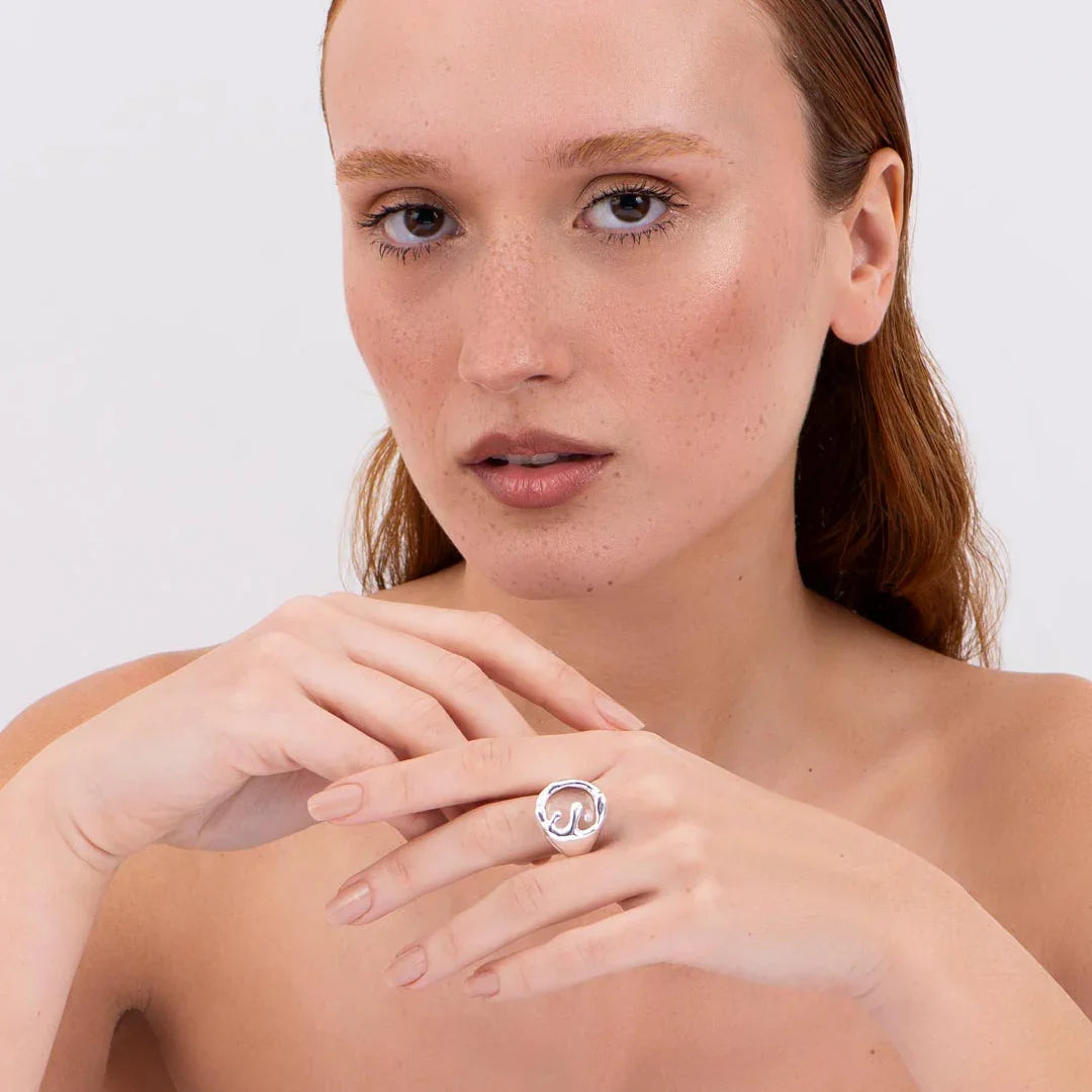 Woman wearing a modern sculptural silver ring on hand, minimalist jewelry close-up