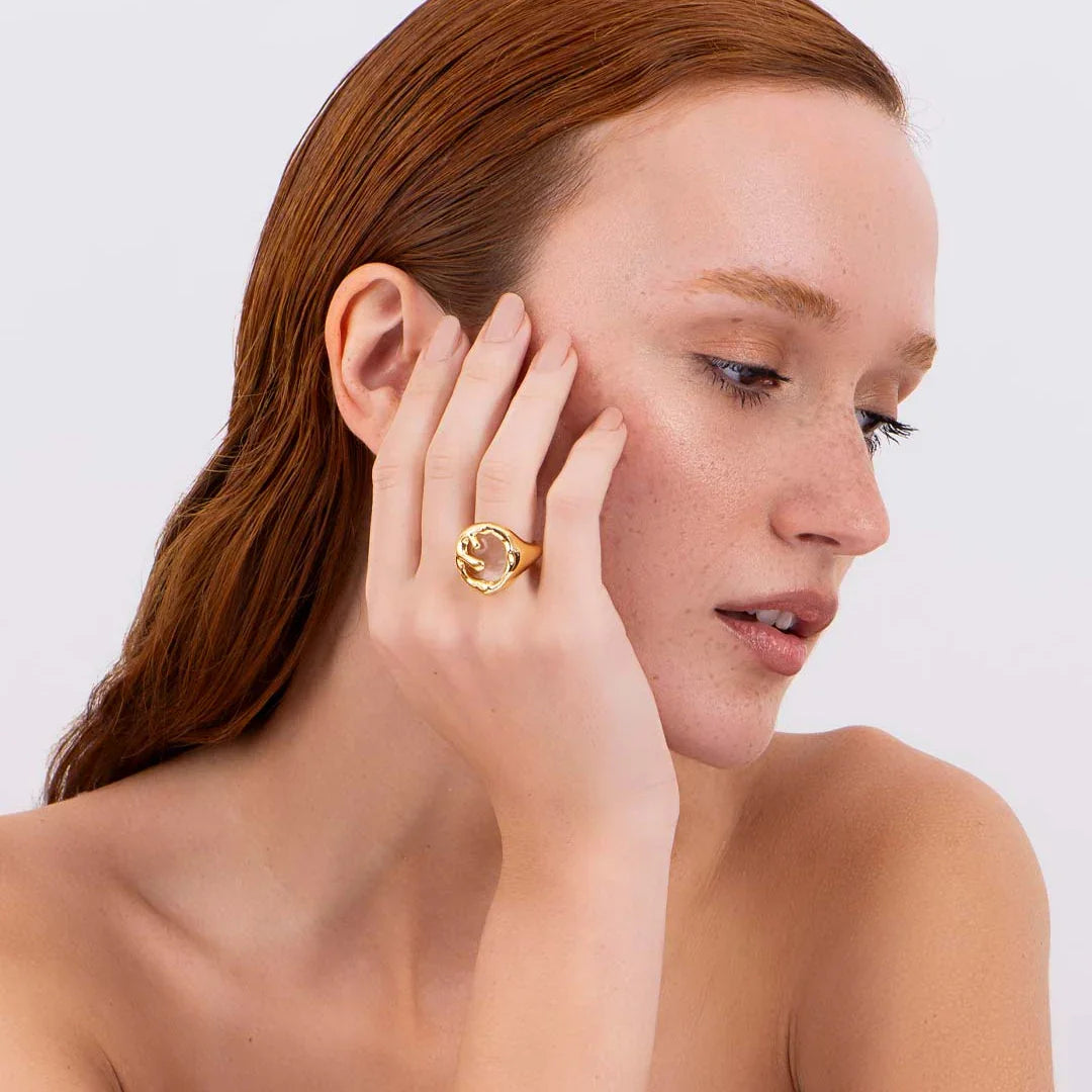 Woman wearing contemporary gold statement ring with organic design, minimal background