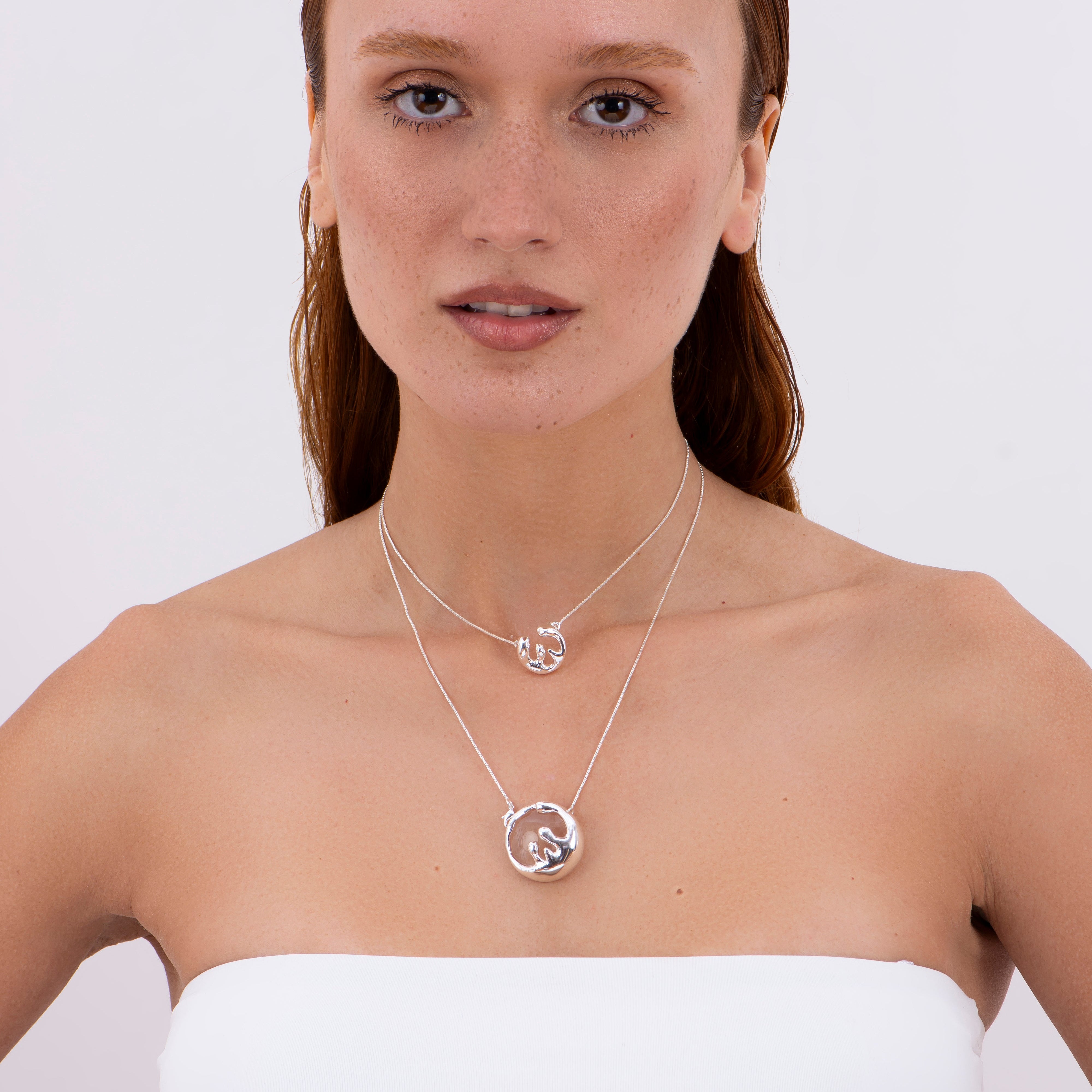 Close-up of model wearing layered silver plated organic necklaces with sculptural fluid pendants from the Organic Motion Collection by Brainstorm Jewelry