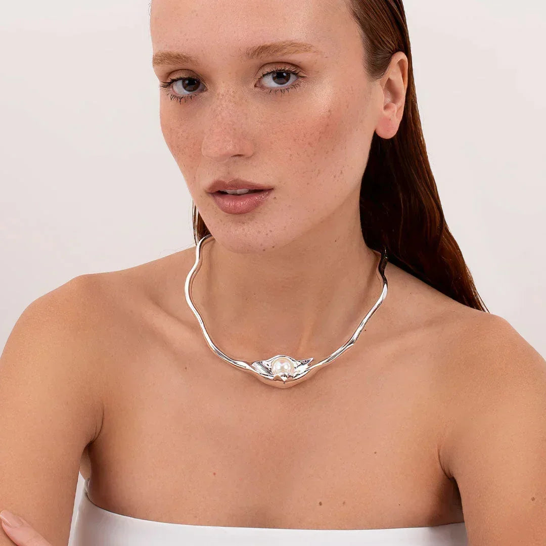 Woman wearing a silver choker necklace with a central pearl, modern jewelry design