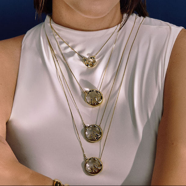 Layered sculptural gold pendant necklaces with organic fluid design