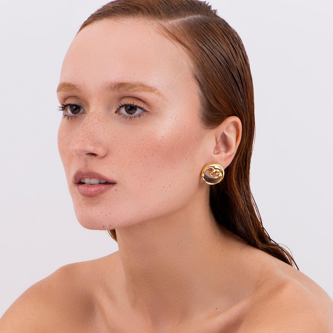 Model wearing organic sculptural gold earrings with modern design